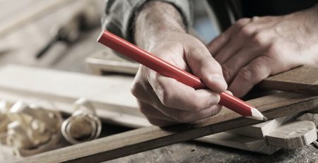 man marking piece of wood to carve